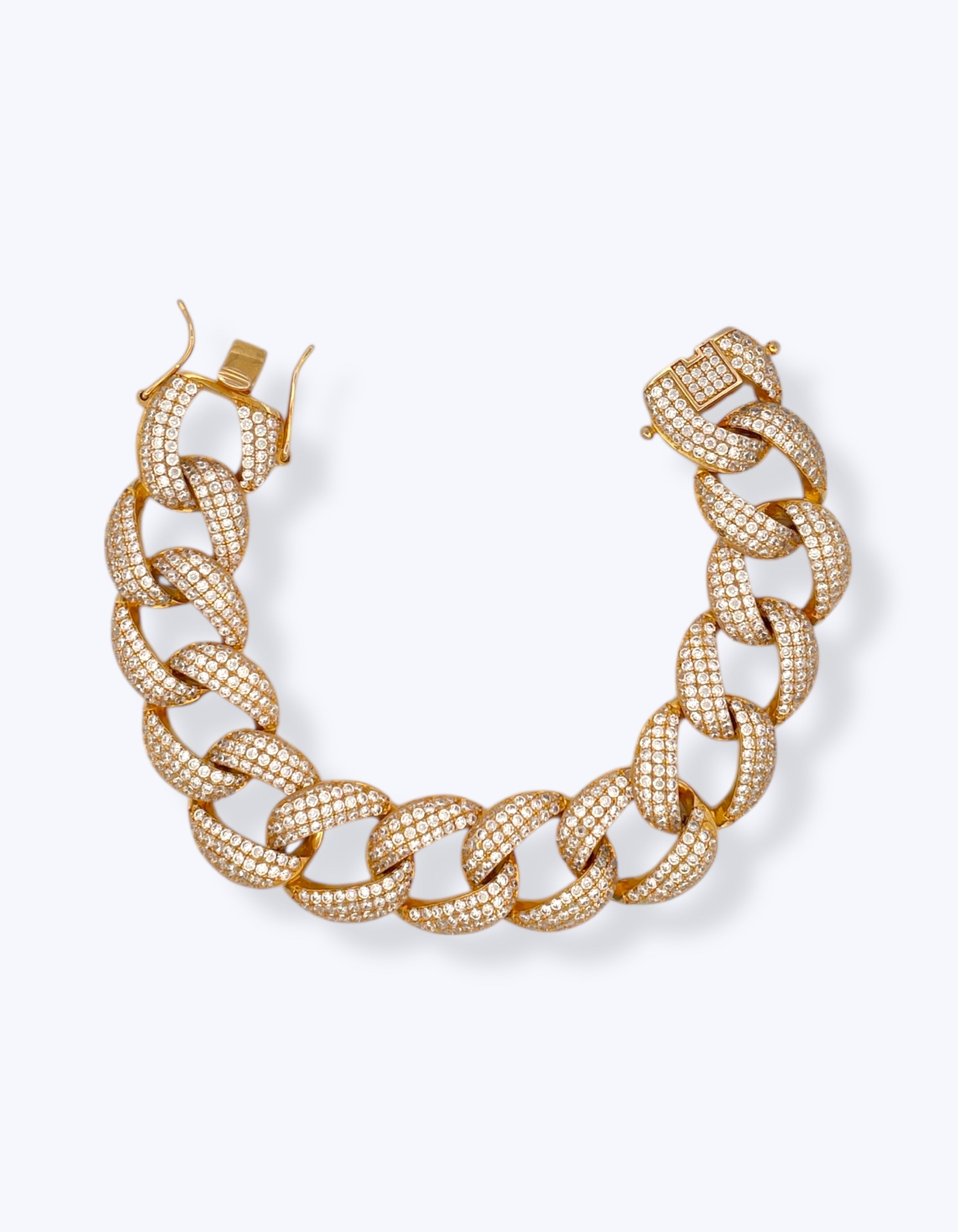Bracciale a catena spessa modello grumetta Cuban Link in Argento 925 placcato oro giallo, interamente ricoperto da un pavé di zirconi bianchi luminosi con chiusura a cassetta di sicurezza aperta su sfondo bianco.