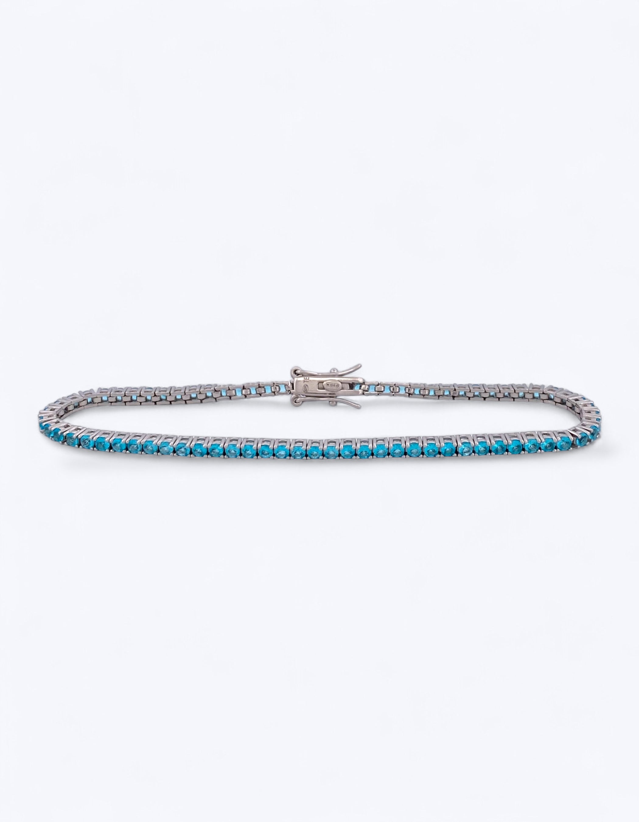 Bracciale tennis flessibile in argento 925 con fila continua di zirconi azzurro oceano taglio brillante e chiusura a cassetta con ganci, su sfondo bianco