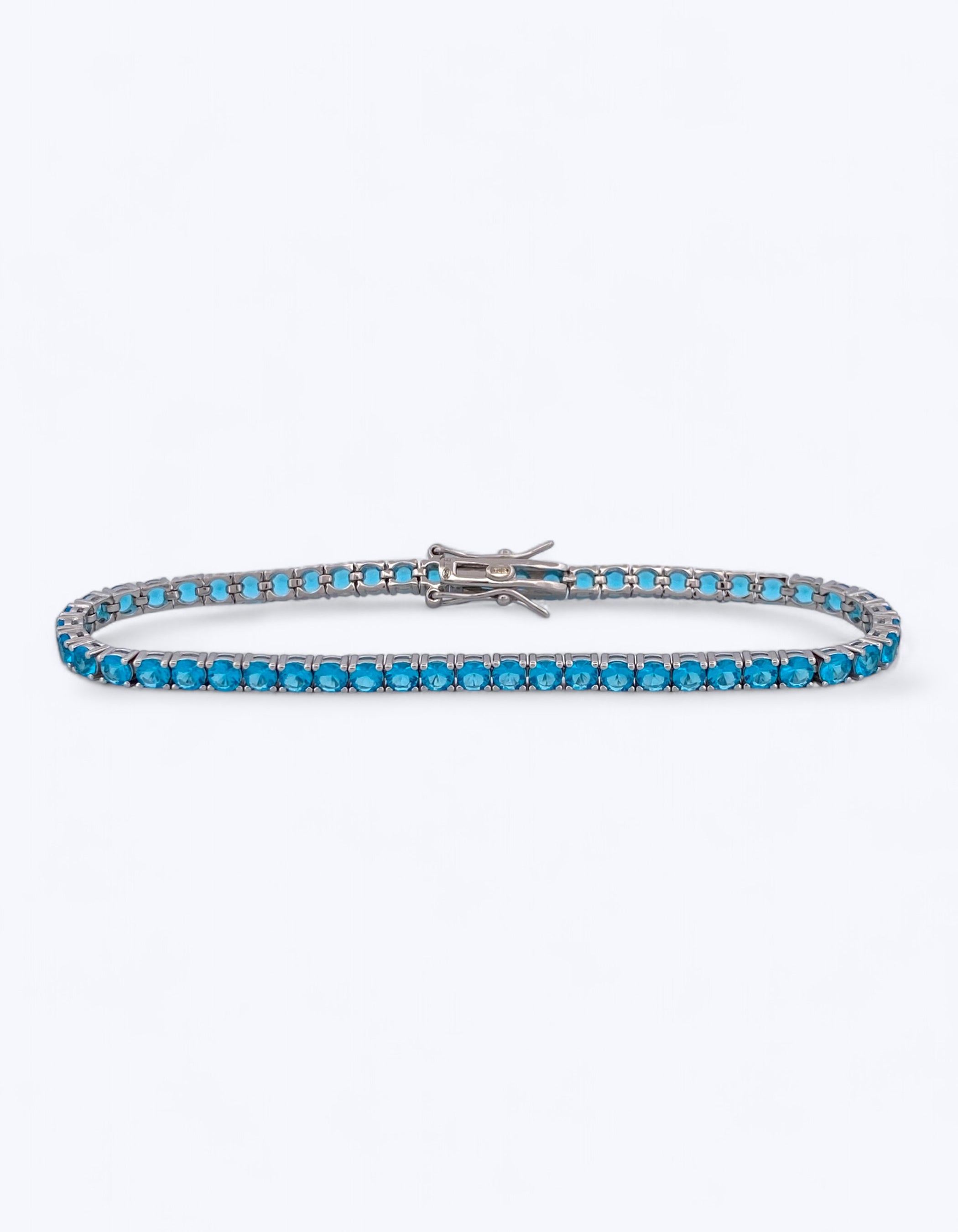 Bracciale tennis flessibile in argento 925 con fila continua di zirconi azzurro oceano taglio brillante e chiusura a cassetta con ganci, su sfondo bianco